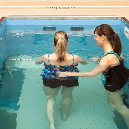 Woman and therapist inside small pool for aquatherapy